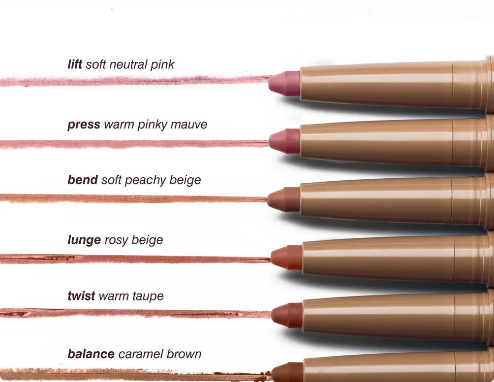 Six cosmetic lip crayons arranged vertically on a white background, each with a text label describing the shade: lift soft neutral pink, press warm pinky mauve, bend soft peachy beige, lunge rosy beige, twist warm taupe, and balance caramel brown. The crayons are tan, and the colored tips are shown with horizontal swatches of the shades.
