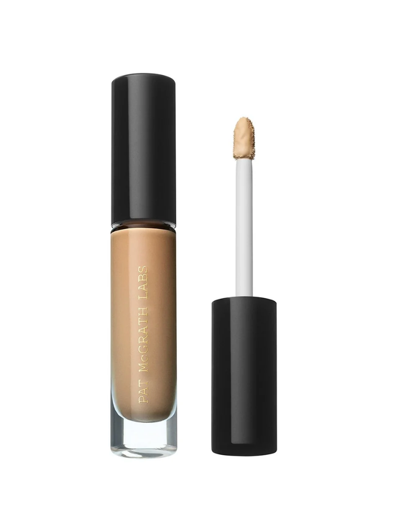 Pat McGrath Labs liquid foundation in a clear bottle with a black cap, shown next to its applicator wand on a white background.