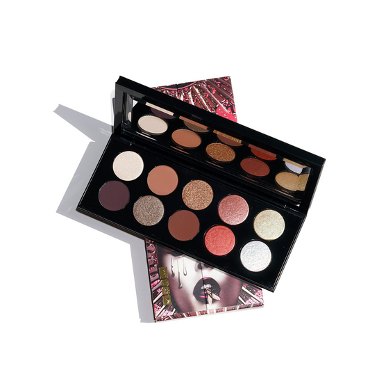 An open 12-pan eyeshadow palette displayed diagonally on top of its patterned outer box against a clean white background. The eyeshadow pans feature a mix of matte, shimmer, and glitter textures in earthy tones like brown, beige, bronze, and red, with one prominent white shimmer pan.